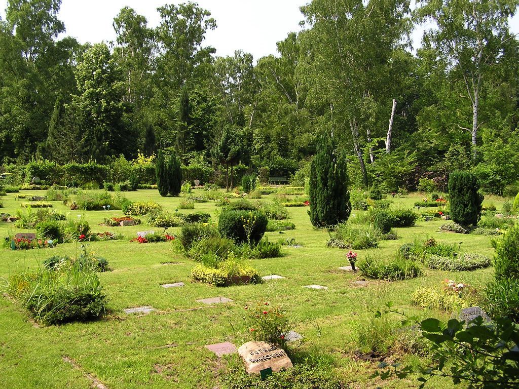 Lawn burial field with flat grave markers and planted beds at Ruhleben Cemetery